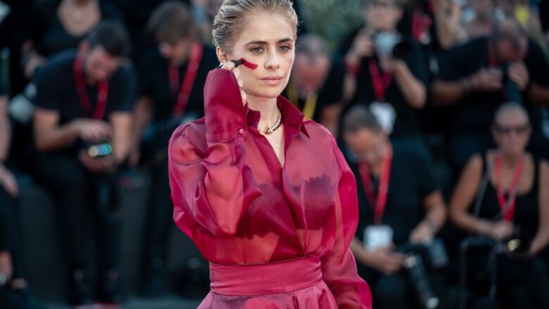 Venezia 2026, dal total red look al segno rosso sul viso contro la violenza sulle donne: l’intenso red carpet di Greta Scarano